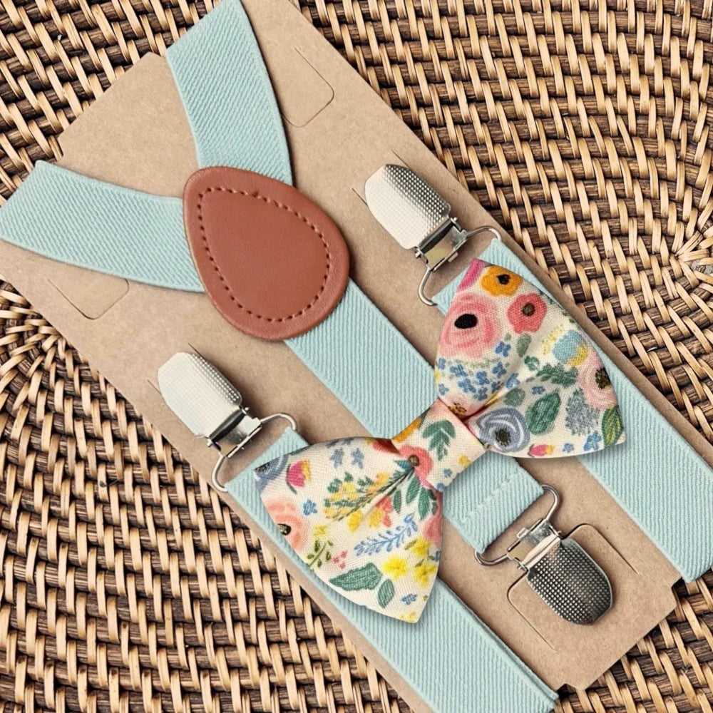 Floral groomsman bow tie and suspenders set on a woven surface