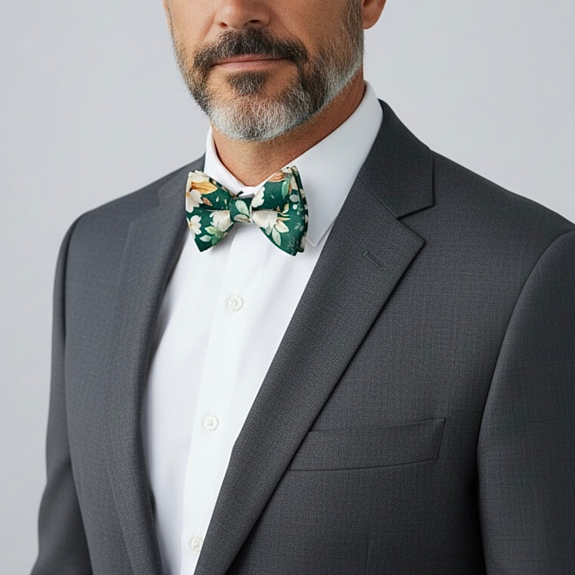 Groomsman in a emerald green floral bow tie and gray suit for a wedding.