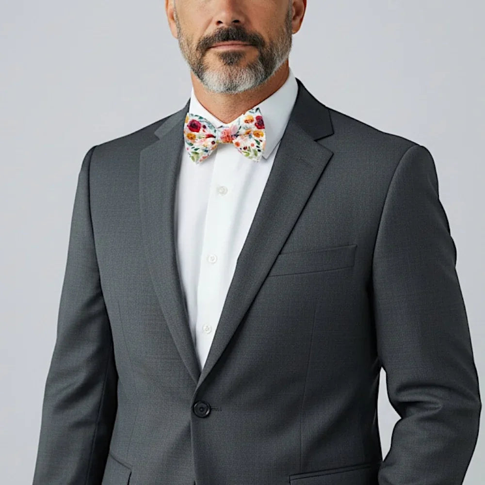 Man wearing a gray suit with a white shirt and wonderland garden floral bow tie on a light gray background