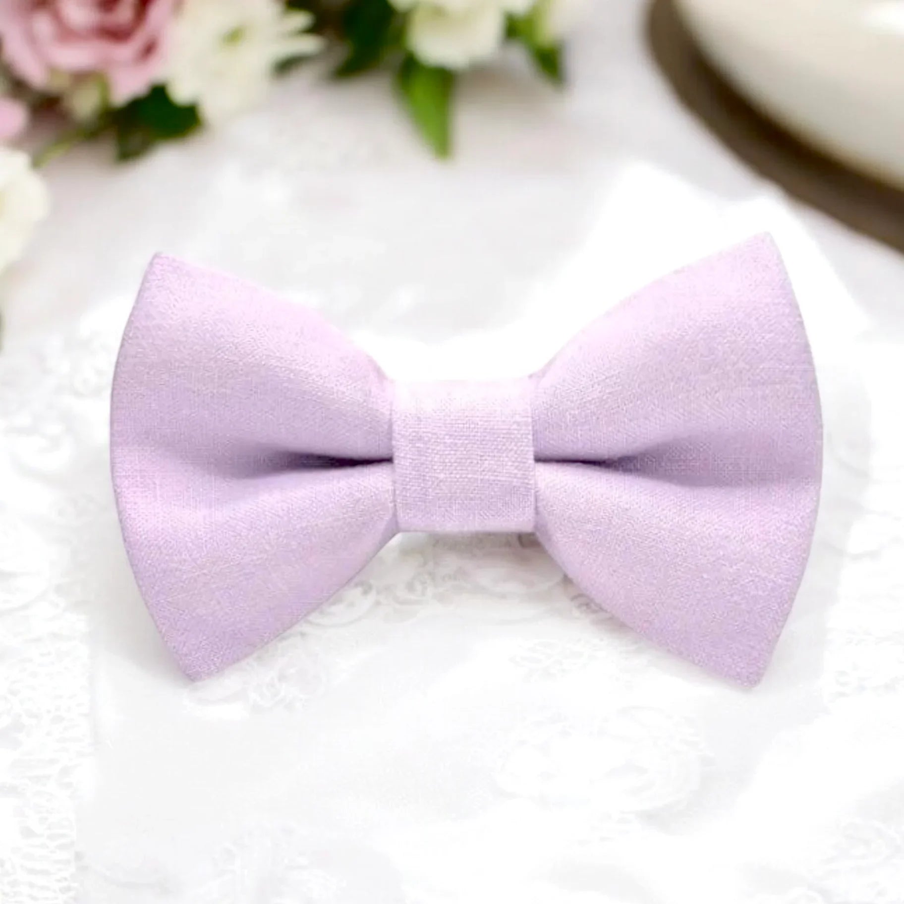 Lavender bow tie on a white background with flowers in the corner