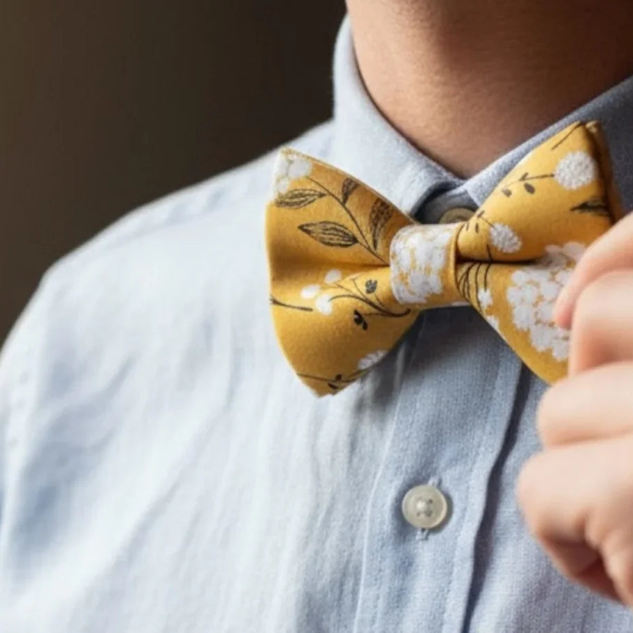 Groomsman wearing a yellow floral bow tie with a blurred background