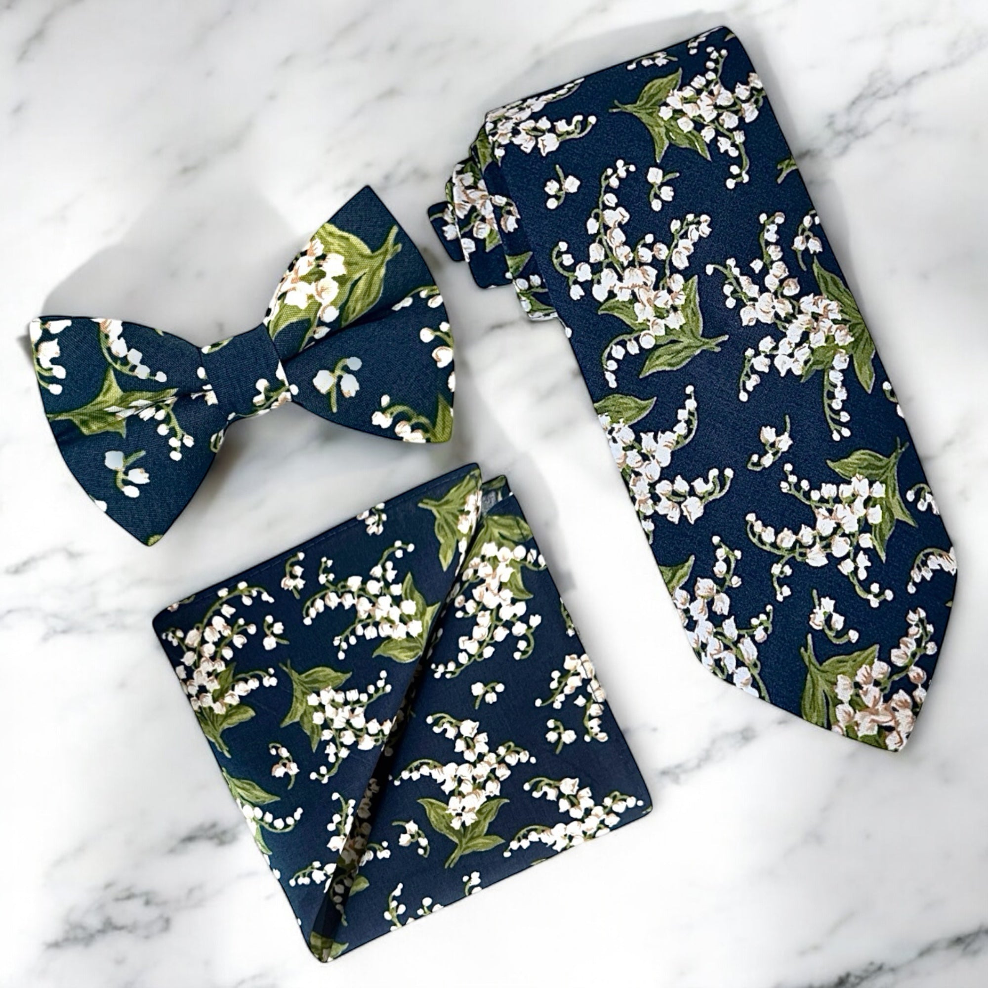 Navy blue and white floral men’s tie, bow tie and pocket square for wedding.