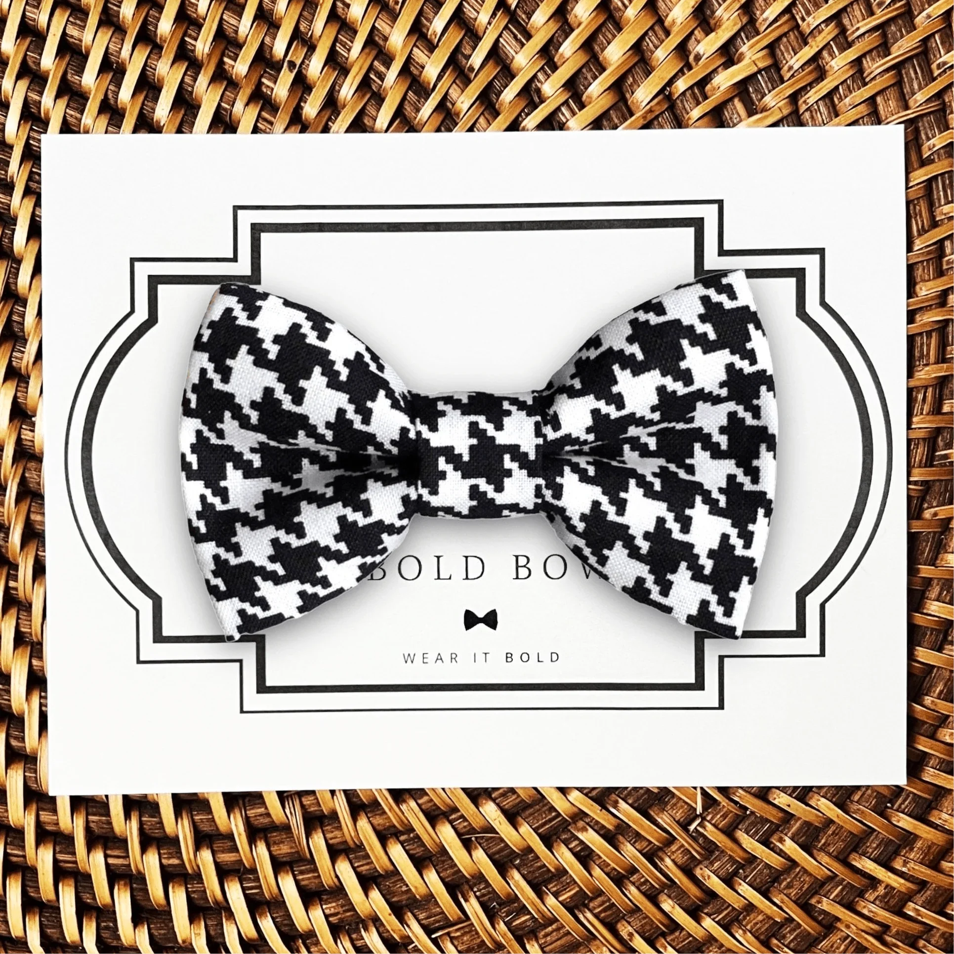 Black and white houndstooth bow tie for dog or cat collar on a white card with a decorative frame against a woven background