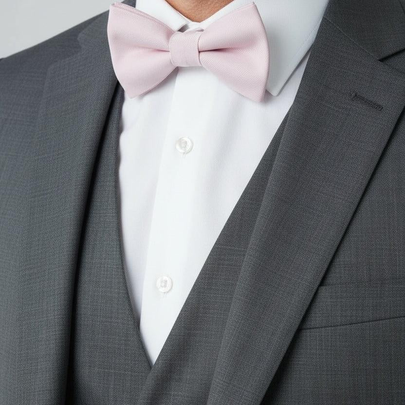Light pink bow tie worn by a man in a suit at a wedding.