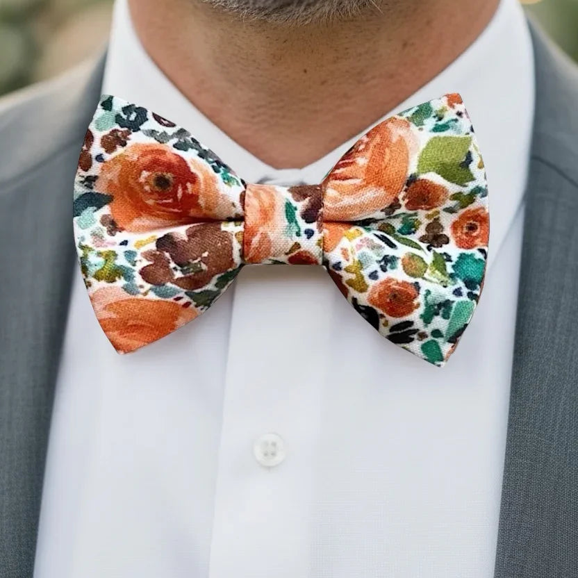 Groomsman wearing an orange floral bow tie with a blurred background