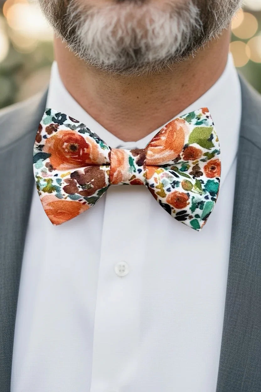 Groomsman wearing an orange floral bow tie with a blurred background