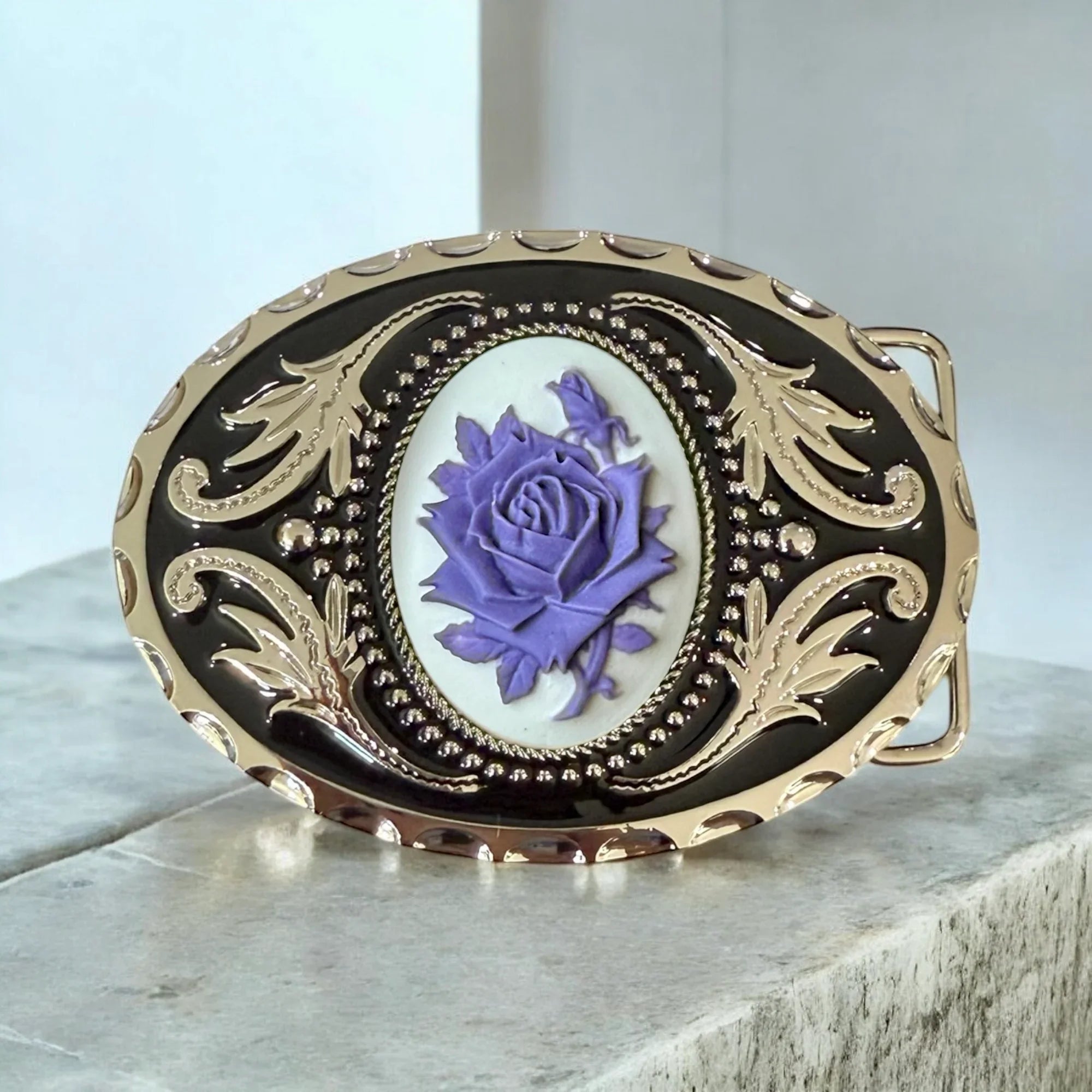 Belt buckle with purple rose design on a light background