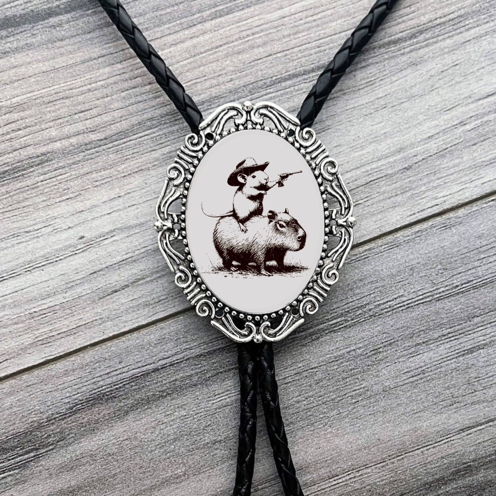 Funny western Bolo tie with capybara and mouse design on a wooden surface