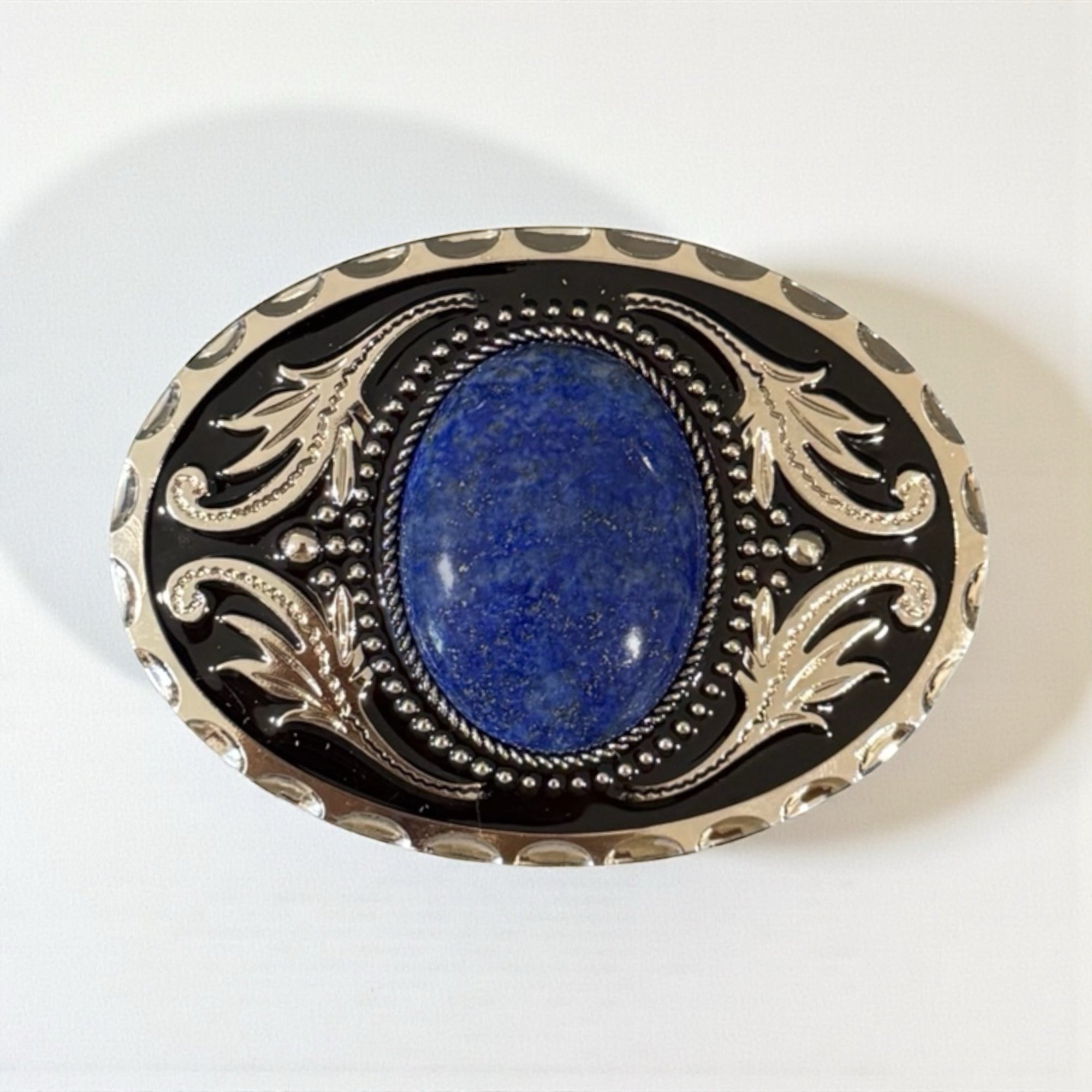 Decorative belt buckle with blue stone and intricate silver design on a white background