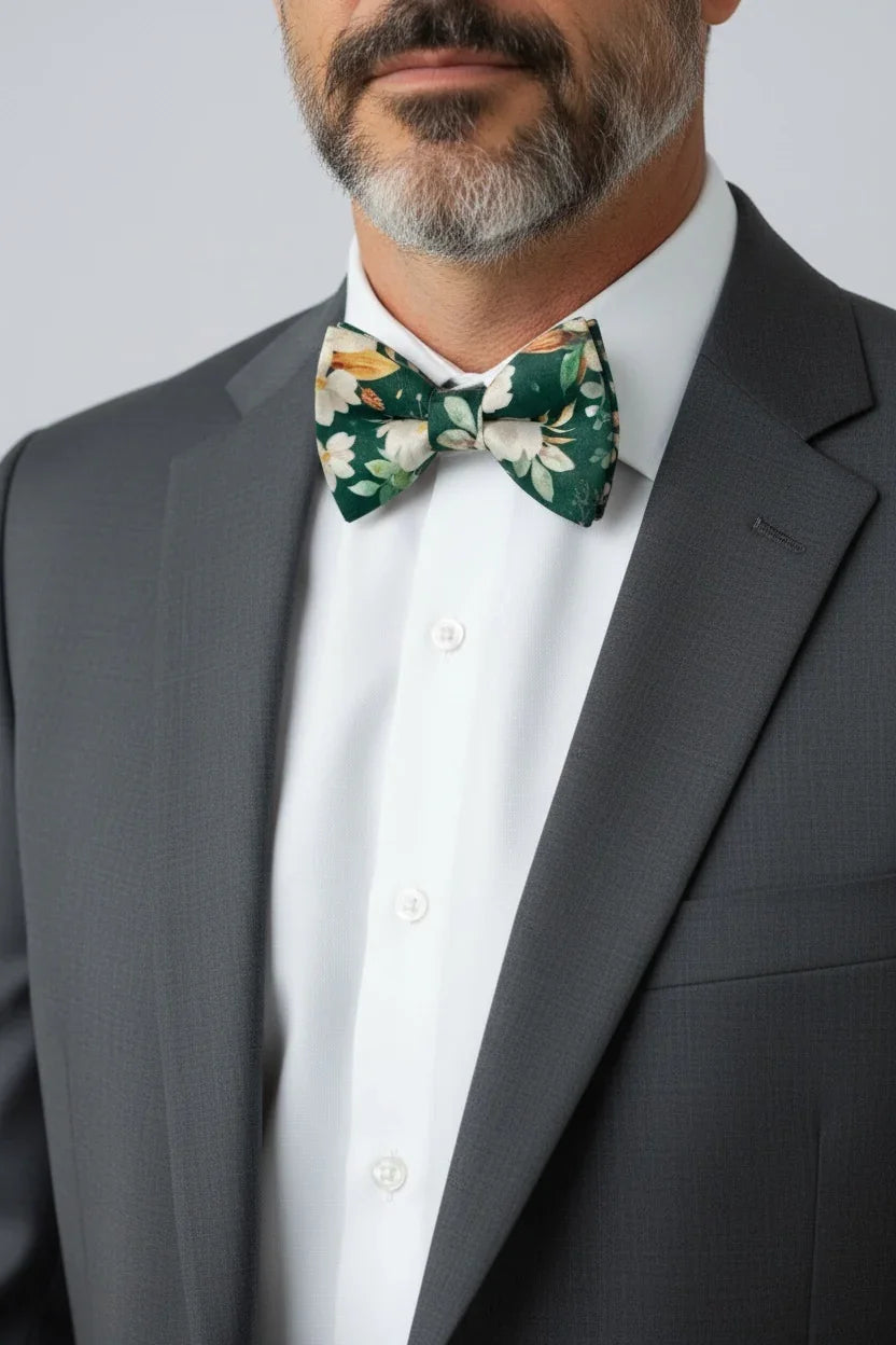 Man wearing a gray suit with a white shirt and a green floral bow tie.