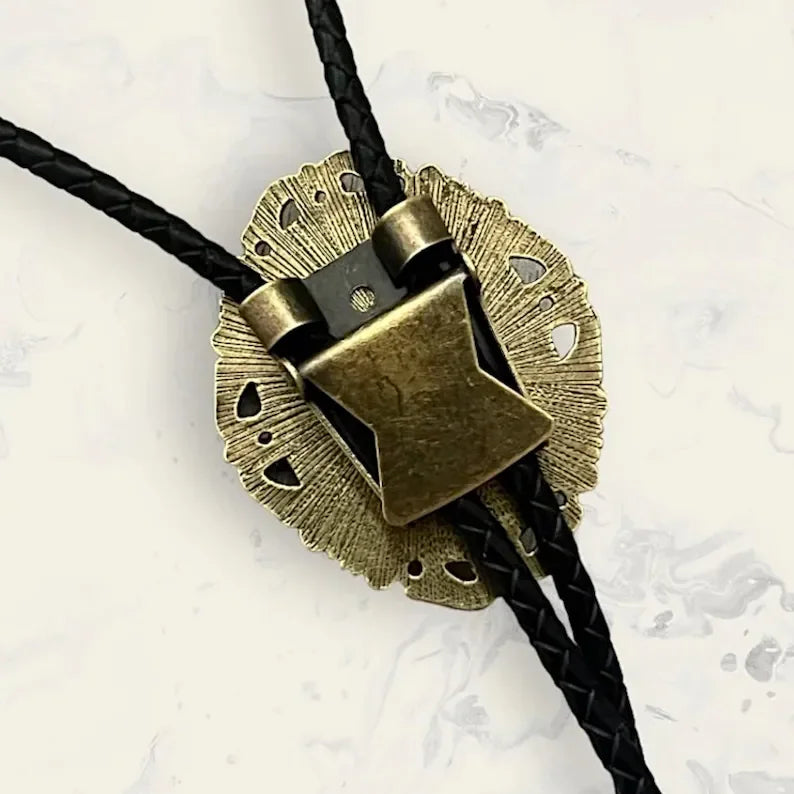 Bronze bolo tie with black cord on a textured white background