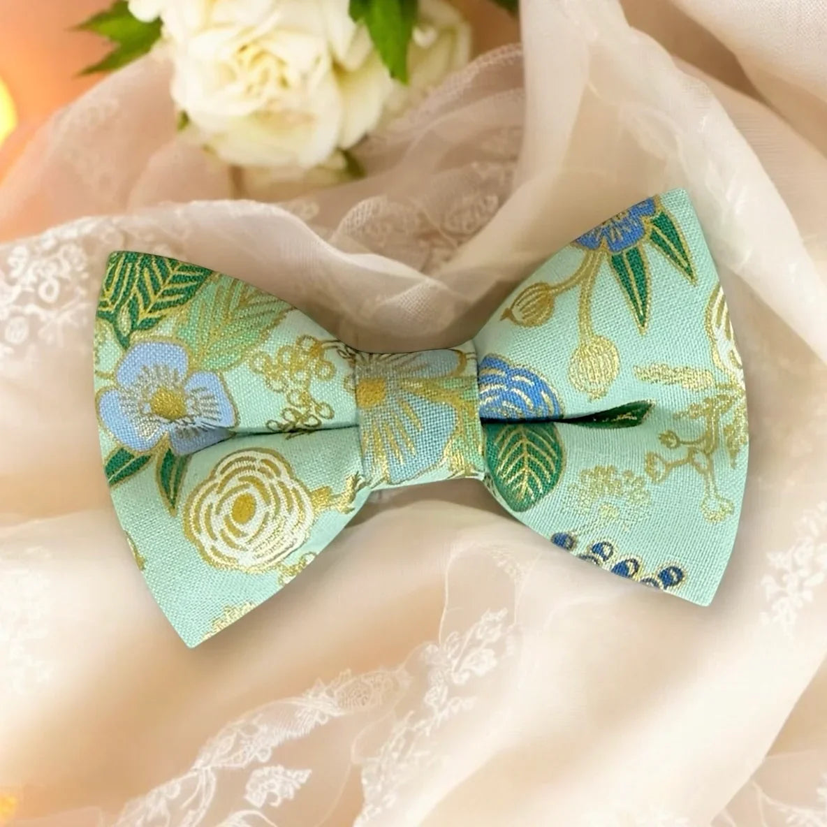 Sage green bow tie on a soft fabric background