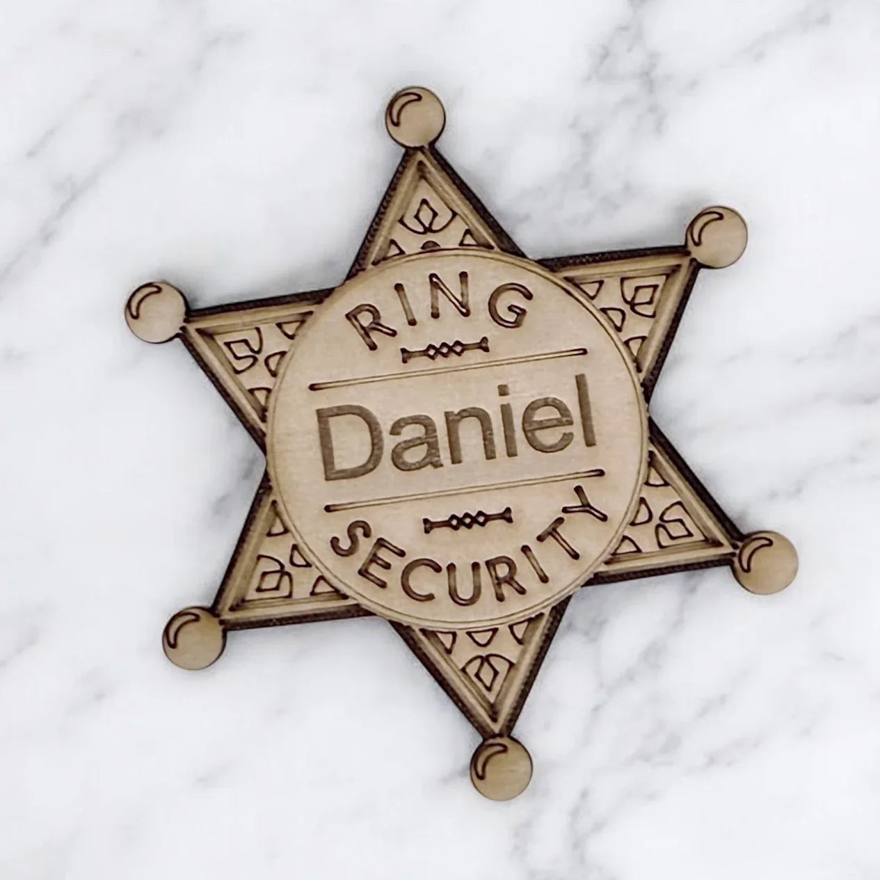 Personalized wooden ring bearer badge with Daniel on a circular center and a decorative star background