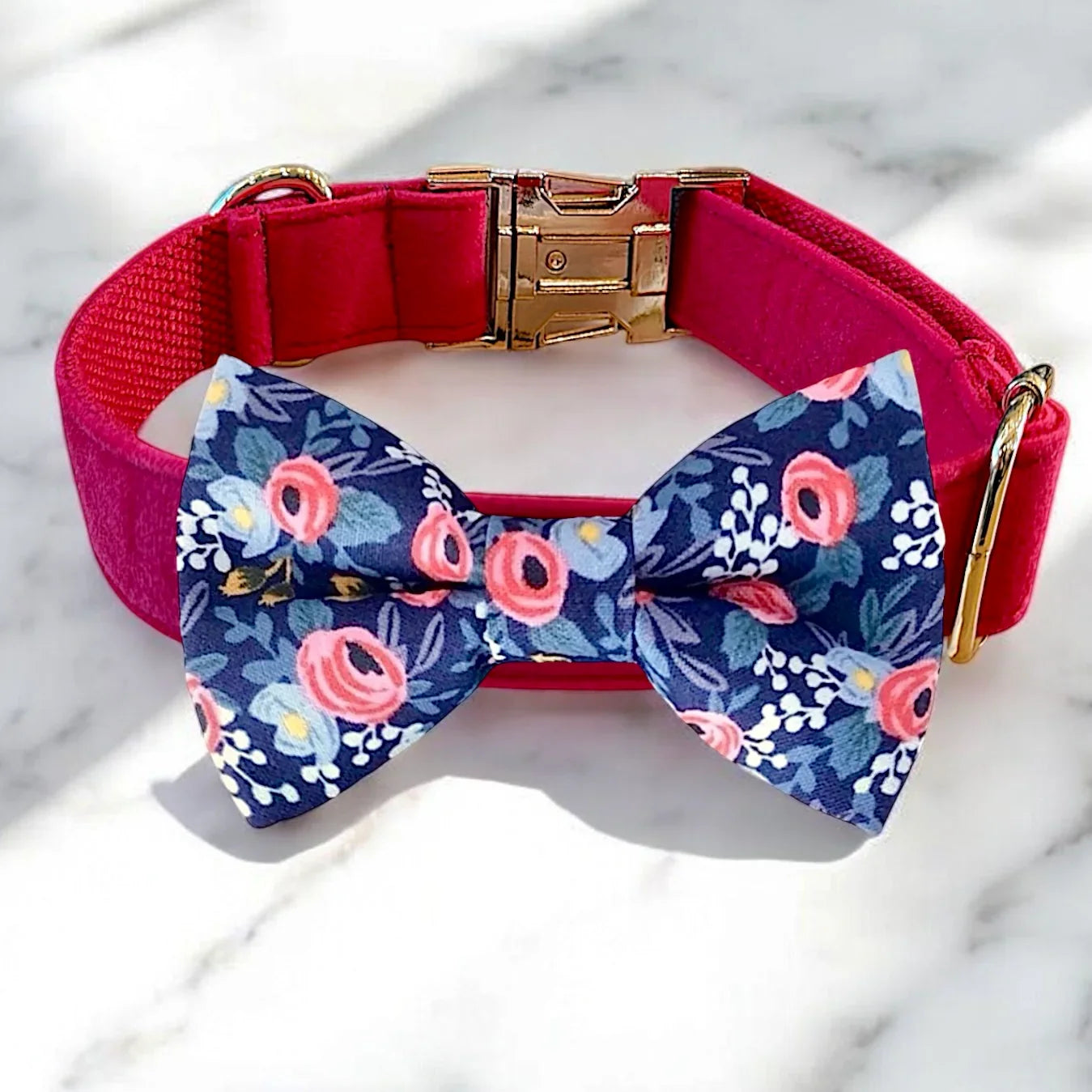 Pink velvet dog collar with a blue floral dog bow tie on a marble surface