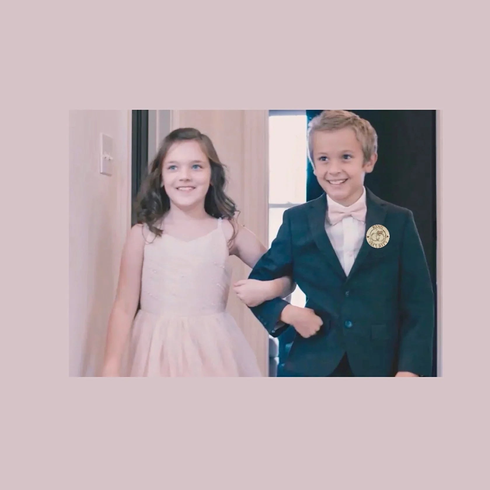 Blush pink bow tie worn by a ring bearer, wearing a ring bearer badge in a wedding with the flower girl.