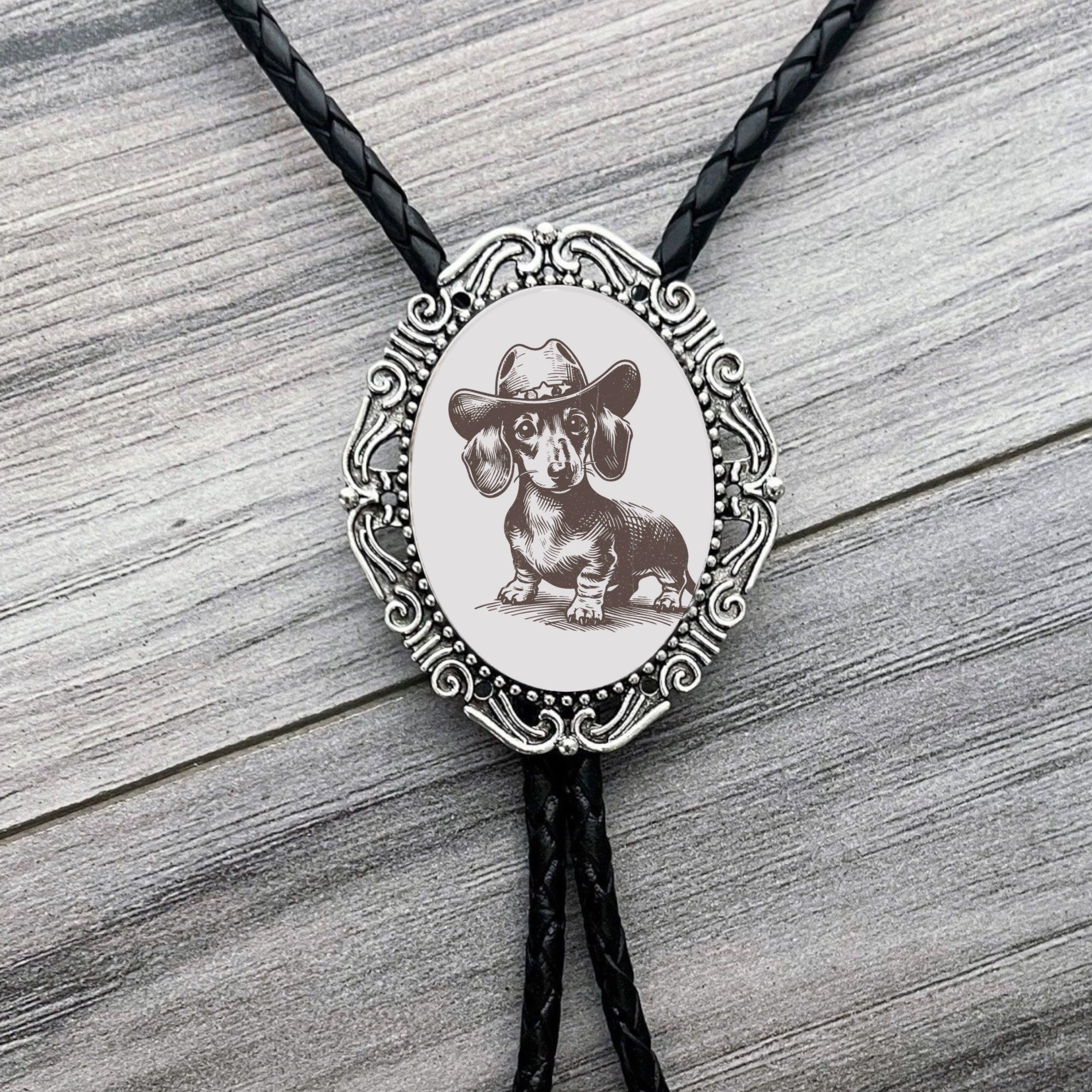 Bolo tie with a dachshund wearing a cowboy hat design on a wooden surface