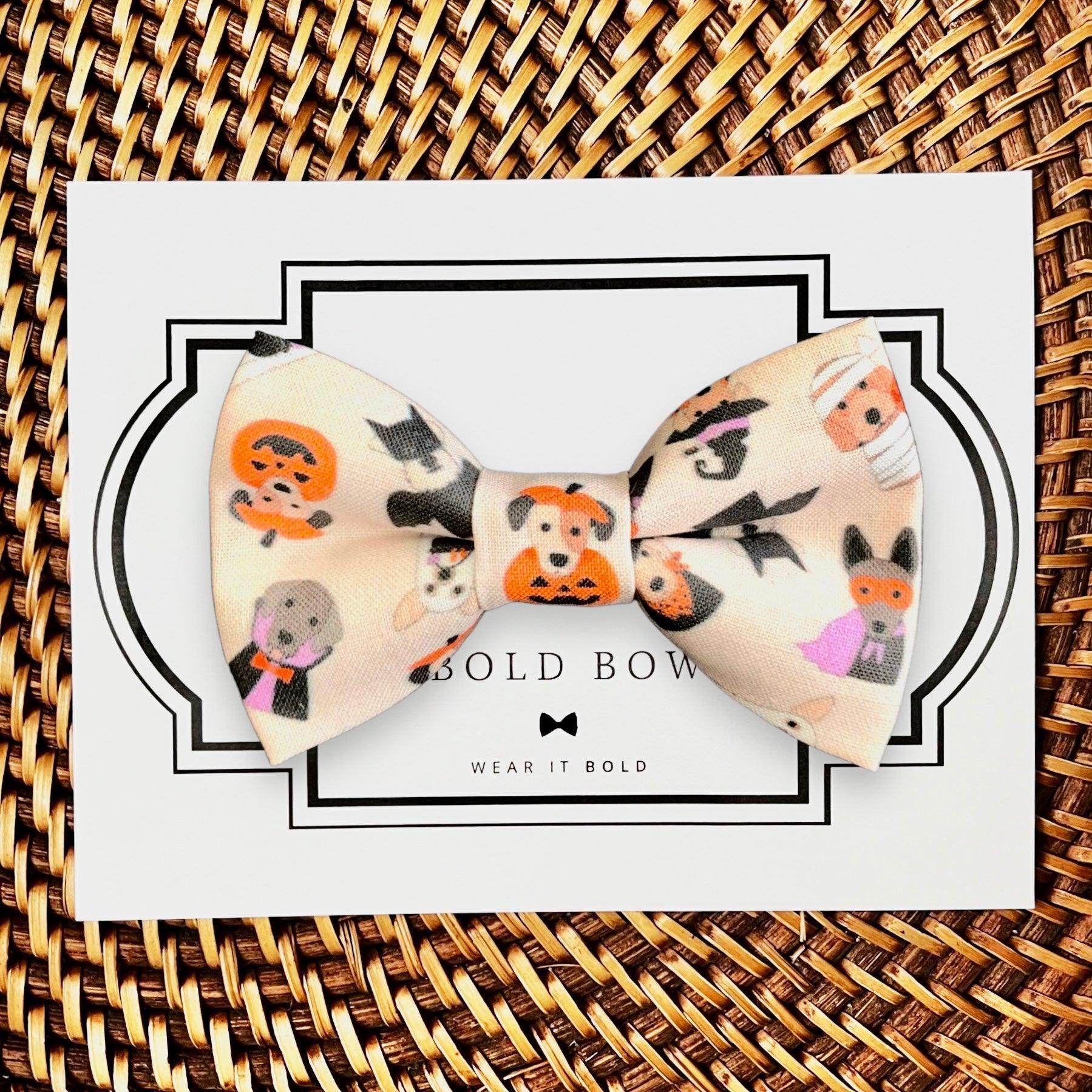Beige Halloween bow tie printed with pumpkins and spooky faces on white packaging against a woven mat