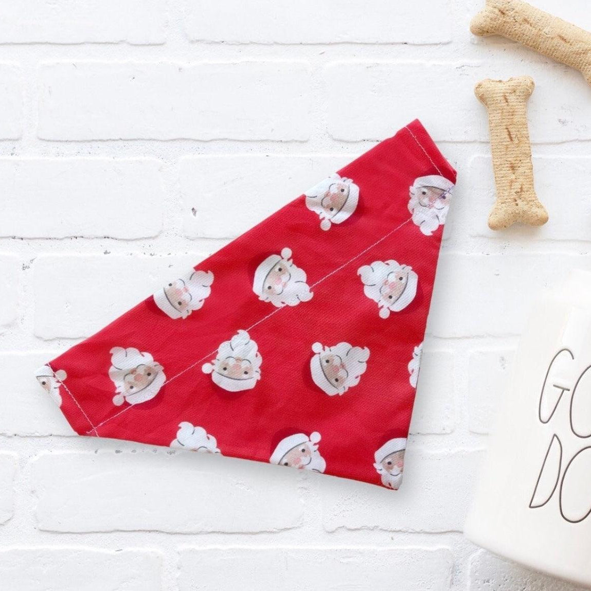 Red Christmas dog bandana with Santa Claus pattern on a white brick background