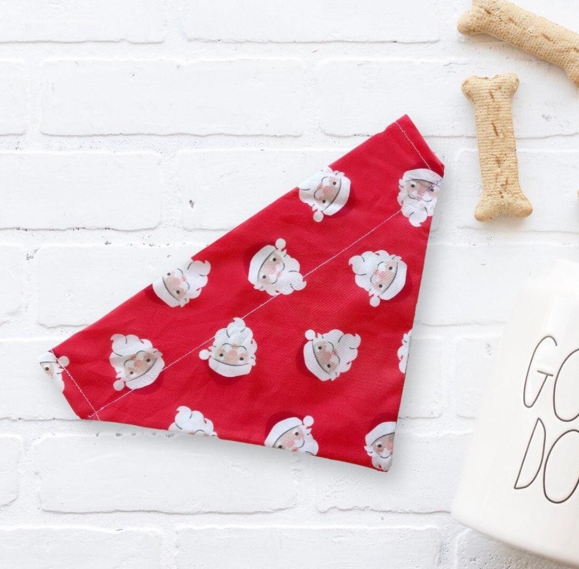 Red Christmas dog bandana with Santa Claus pattern on a white brick background
