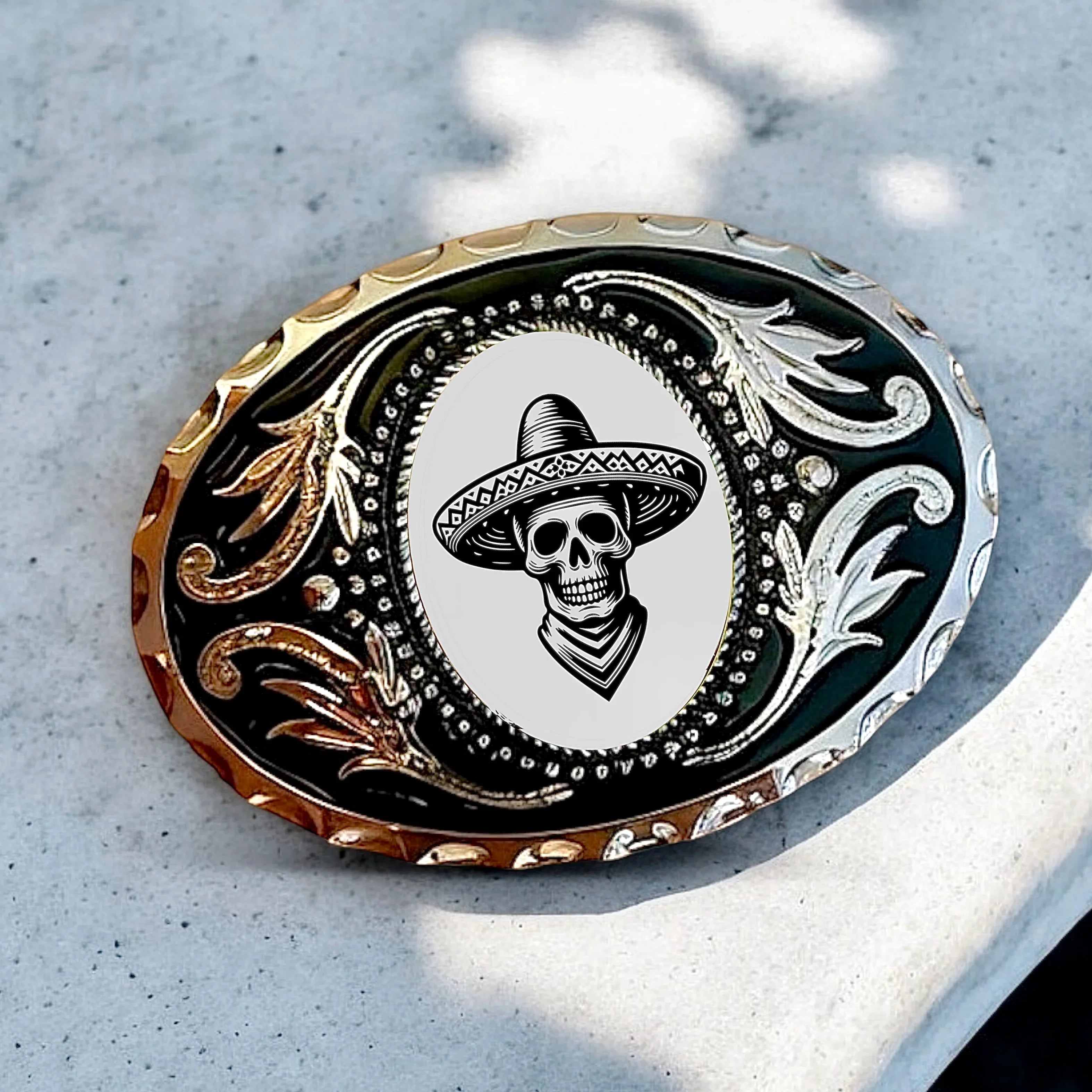 Decorative belt buckle with skull and sombrero design on a textured surface