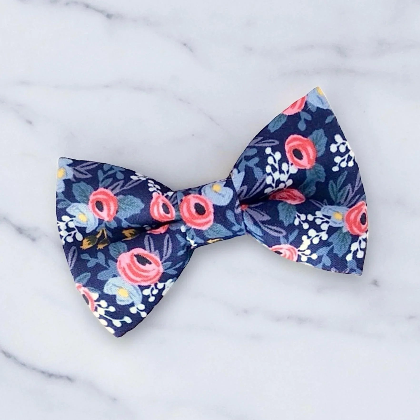 Size chart for pre-tied bow ties from The Bold Bow Tie detailing measurements across three sizes. Small is 3.5 inches wide and recommended for ages 6 months to 5 years. Medium is 4 inches wide and recommended for ages 6 to 12 years. Large is 4.5 inches wide and recommended for ages 13 years and up. Visual icons illustrate the relative sizes with horizontal arrows showing that width is measured from wingtip to wingtip. Bottom text notes that all bow ties are pre-tied and ready to add to your outfit.