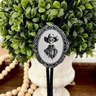 Silver Bolo Tie- Skeleton Cowboy displayed on a decorative boxwood arrangement.