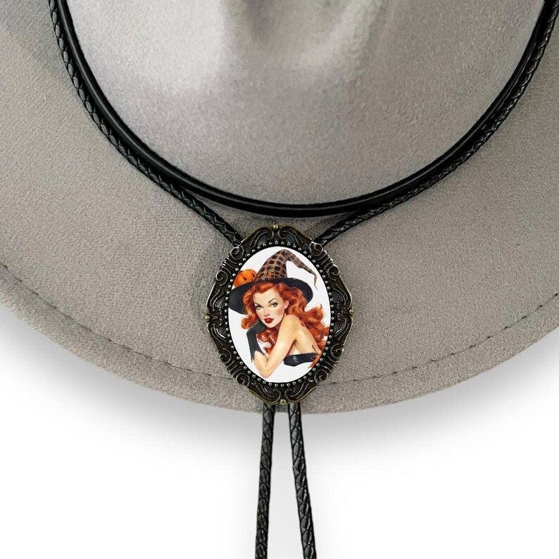 Oval bolo tie pendant featuring a redheaded witch in a vintage illustration framed by ornate metal with braided cords.