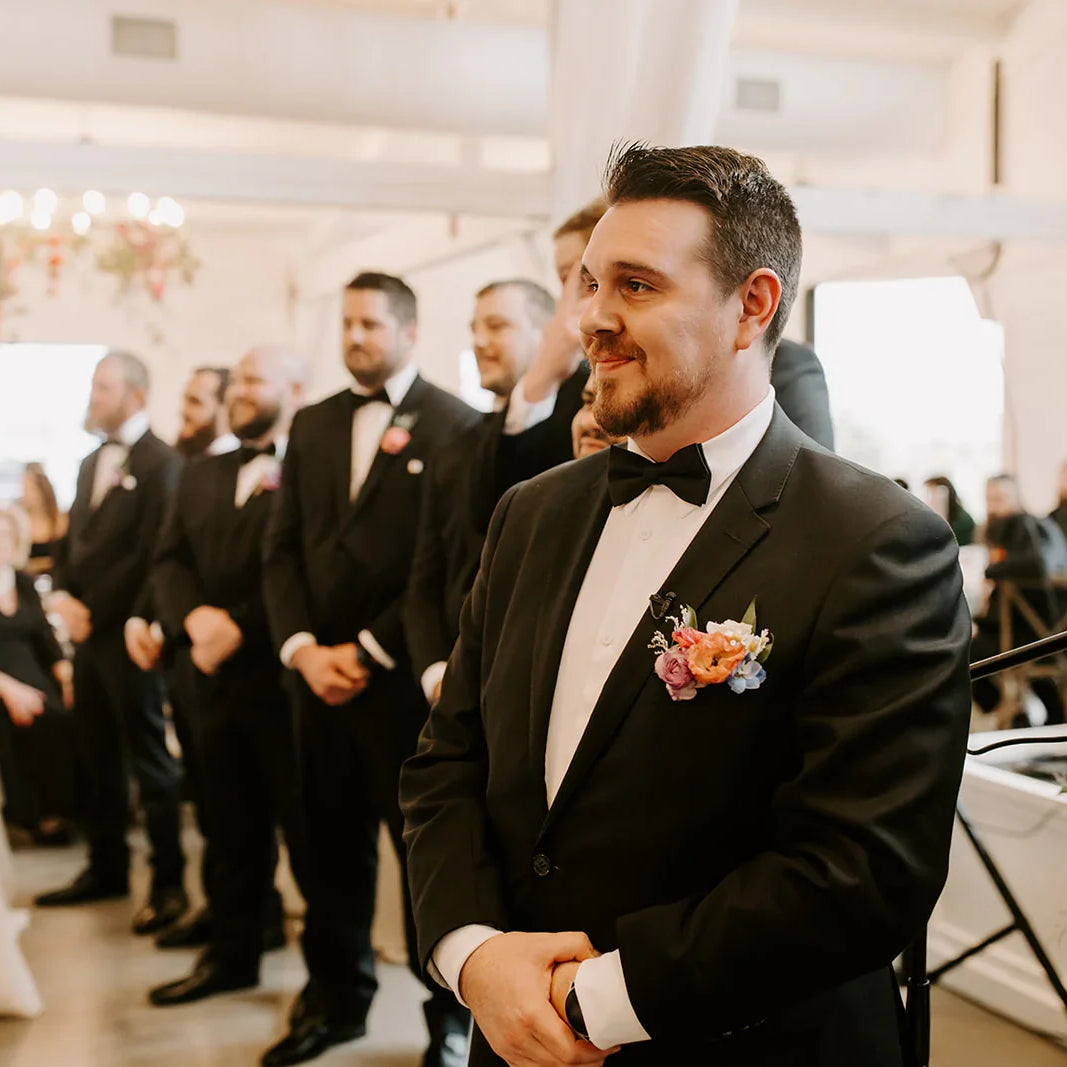 Satin black bow tie being worn by a groom at a wedding.