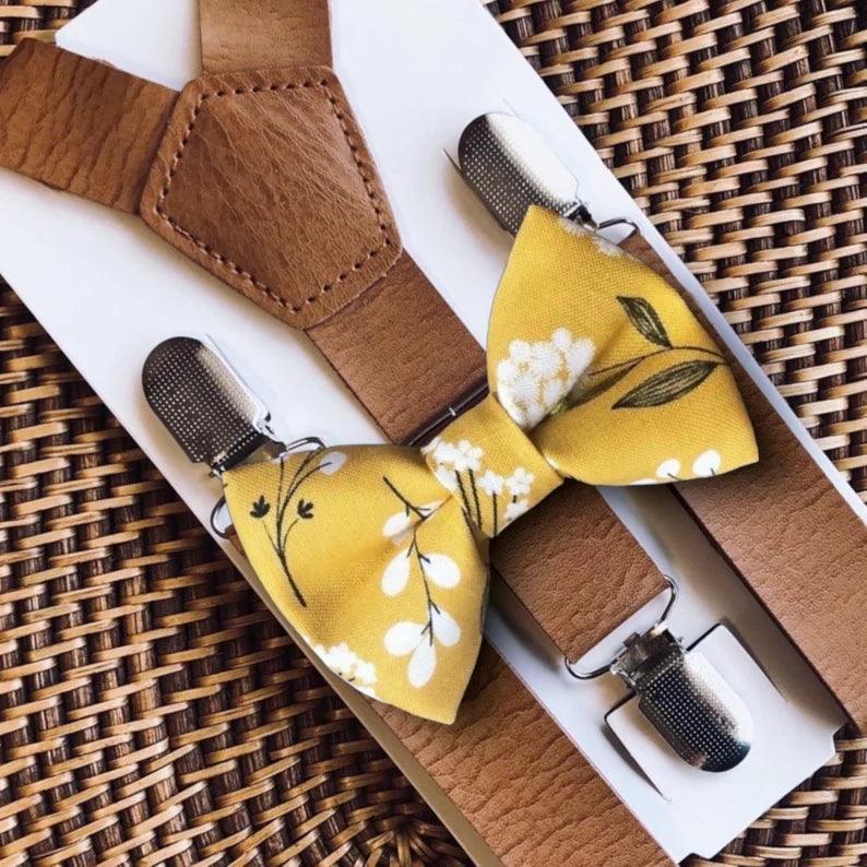 Yellow floral bow tie with brown suspenders on a woven surface