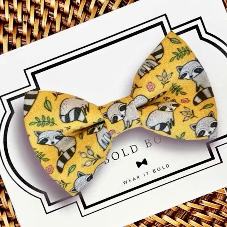Yellow raccoon print bow tie displayed on a white branding card