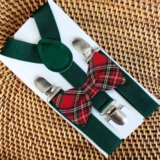 Green suspenders with red plaid bow tie on a white box against a woven background