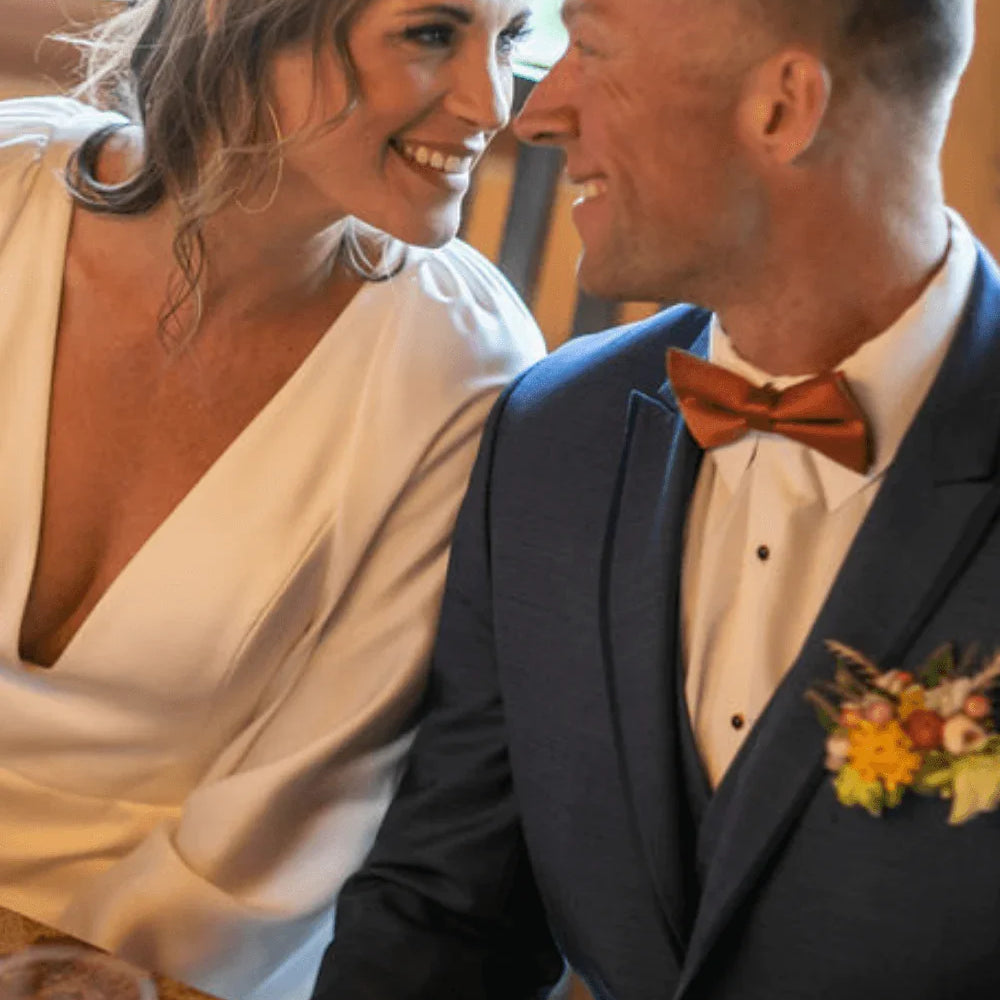 Man in a terracotta bow tie with his bride.