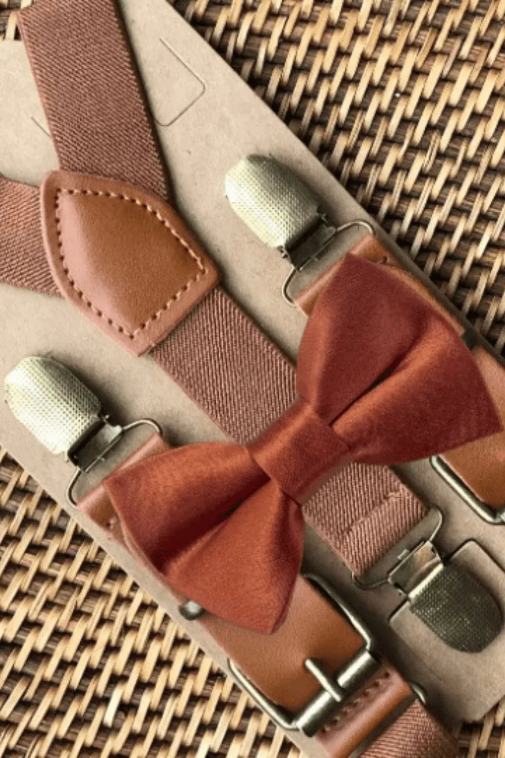 Terracotta bow tie and suspenders on a woven tray with brass clips.