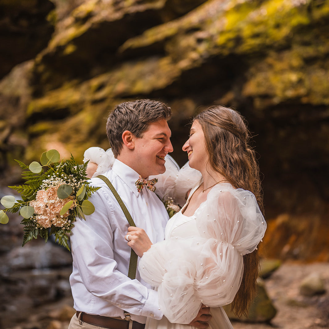 Bride and groom smiling and embracing in a rustic wedding setting.