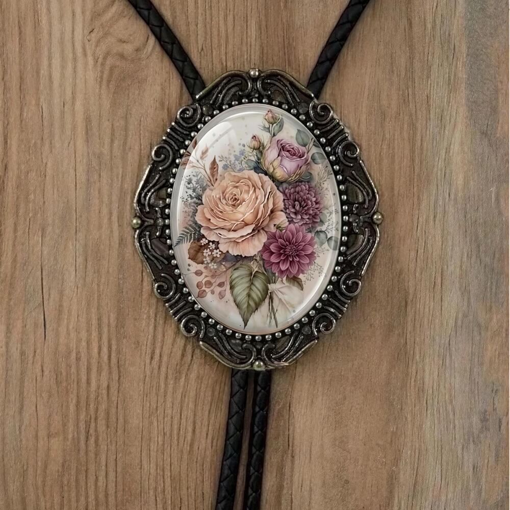 A decorative pendant featuring a floral design, including a rose and various other flowers, is displayed on a wooden surface.
