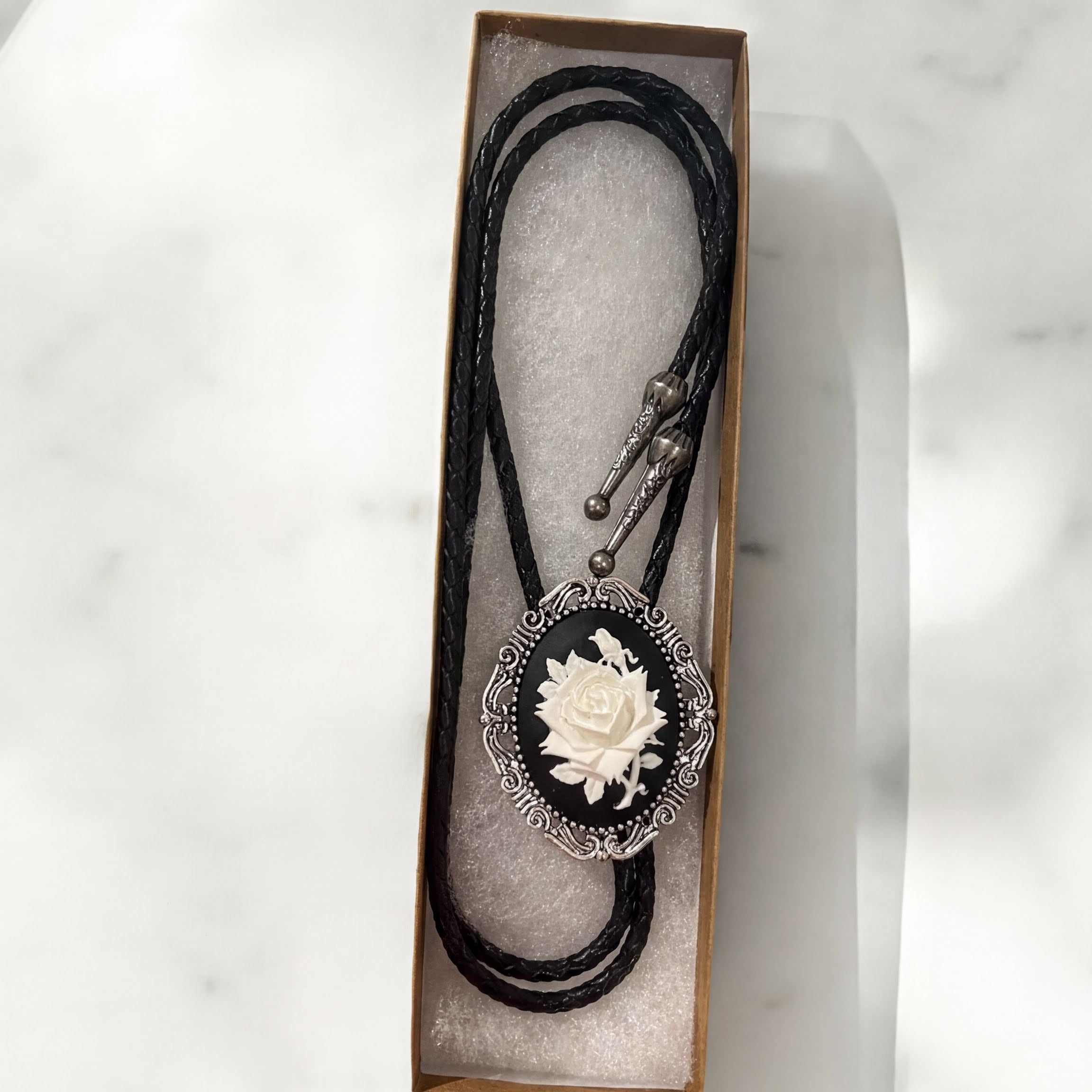 White rose silver bolo tie and leather cord.