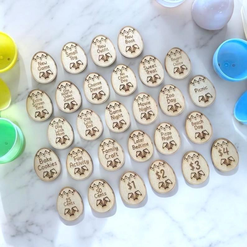 Group of wooden Easter tokens with activity labels laid out on a white marble surface with colorful eggs nearby