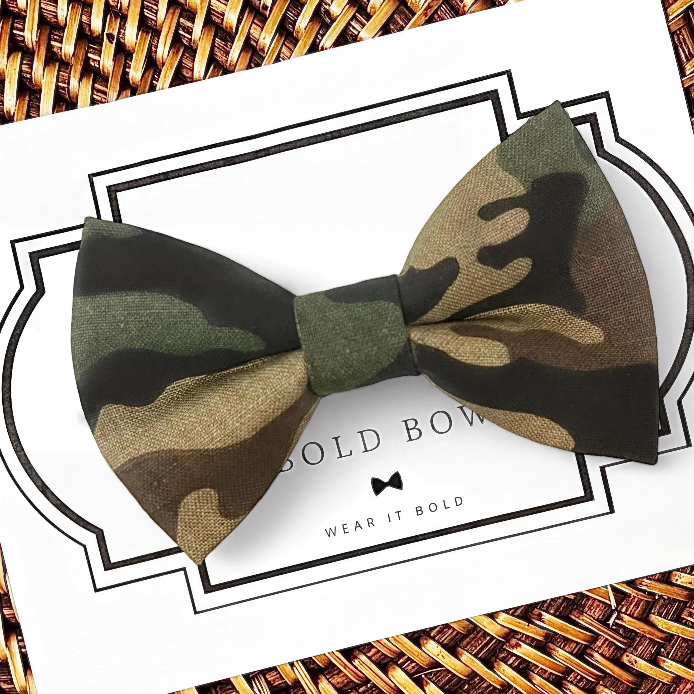 A camouflage bow tie is displayed on a white background with a black border.