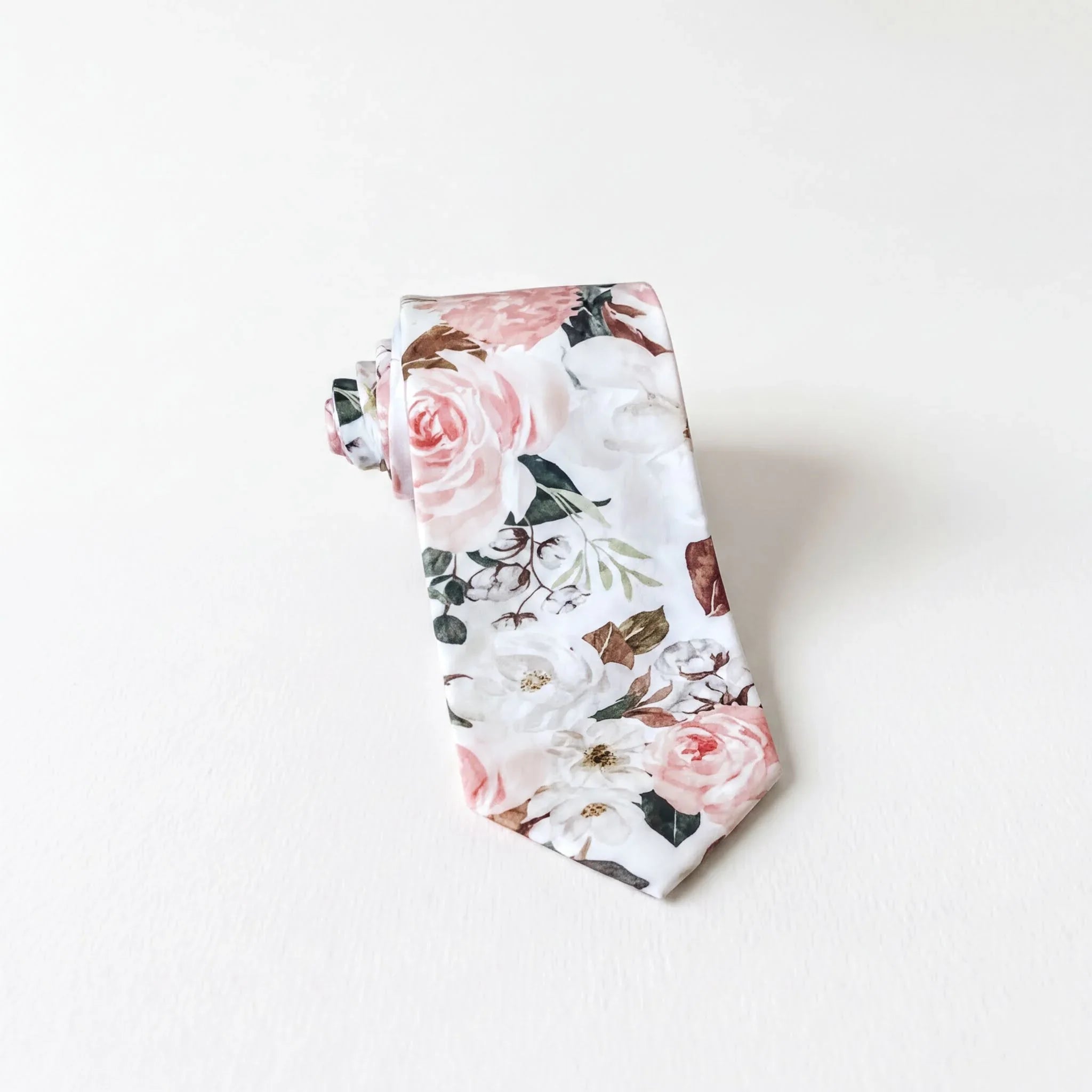 A tie with a floral print pattern, featuring white and pink flowers, is displayed against a white background.