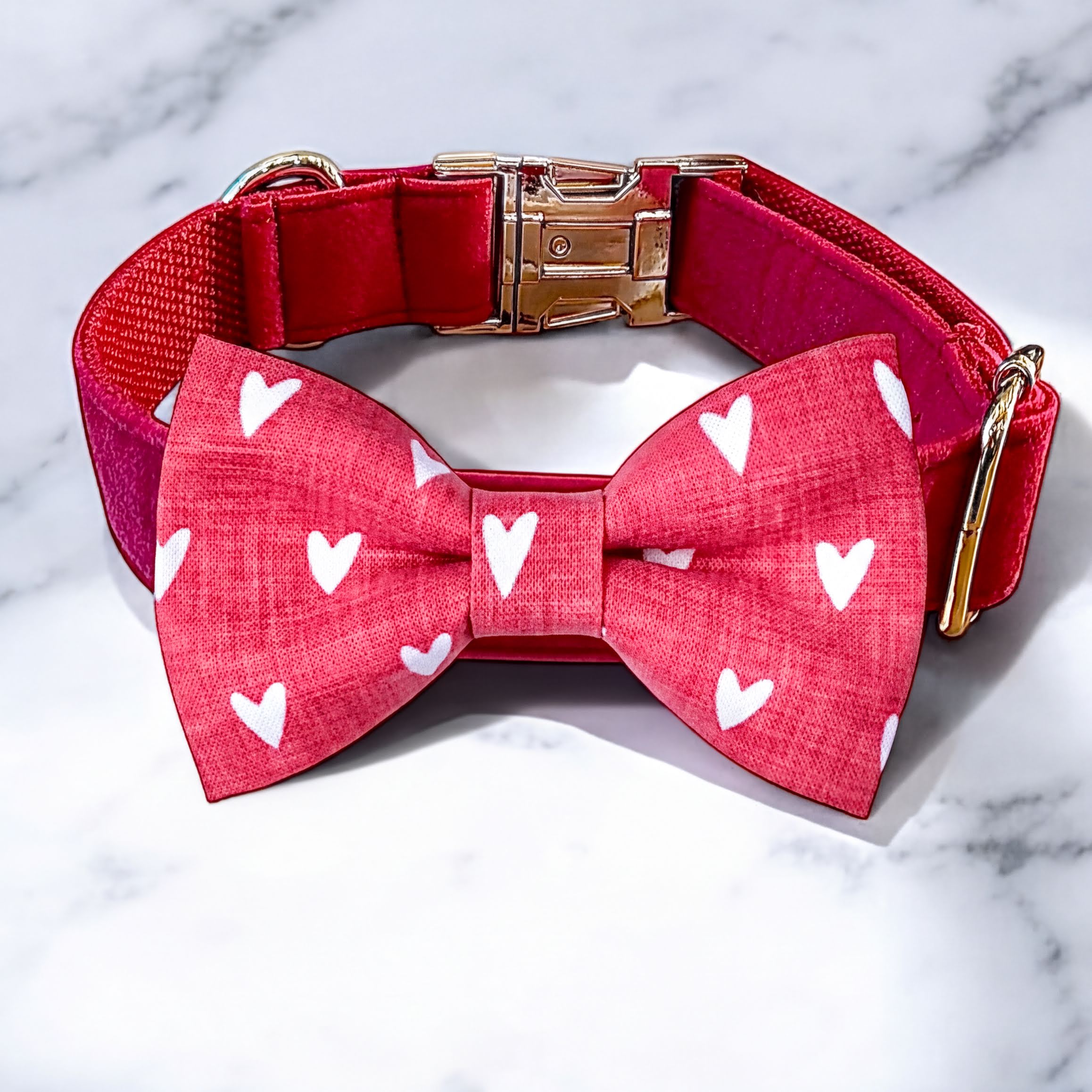 Pink dog bow tie collar with white hearts on a marble background