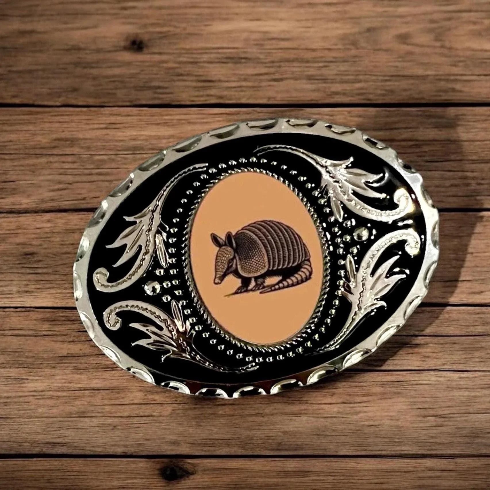 Orange armadillo belt buckle for men and women with armadillo design on a wooden surface