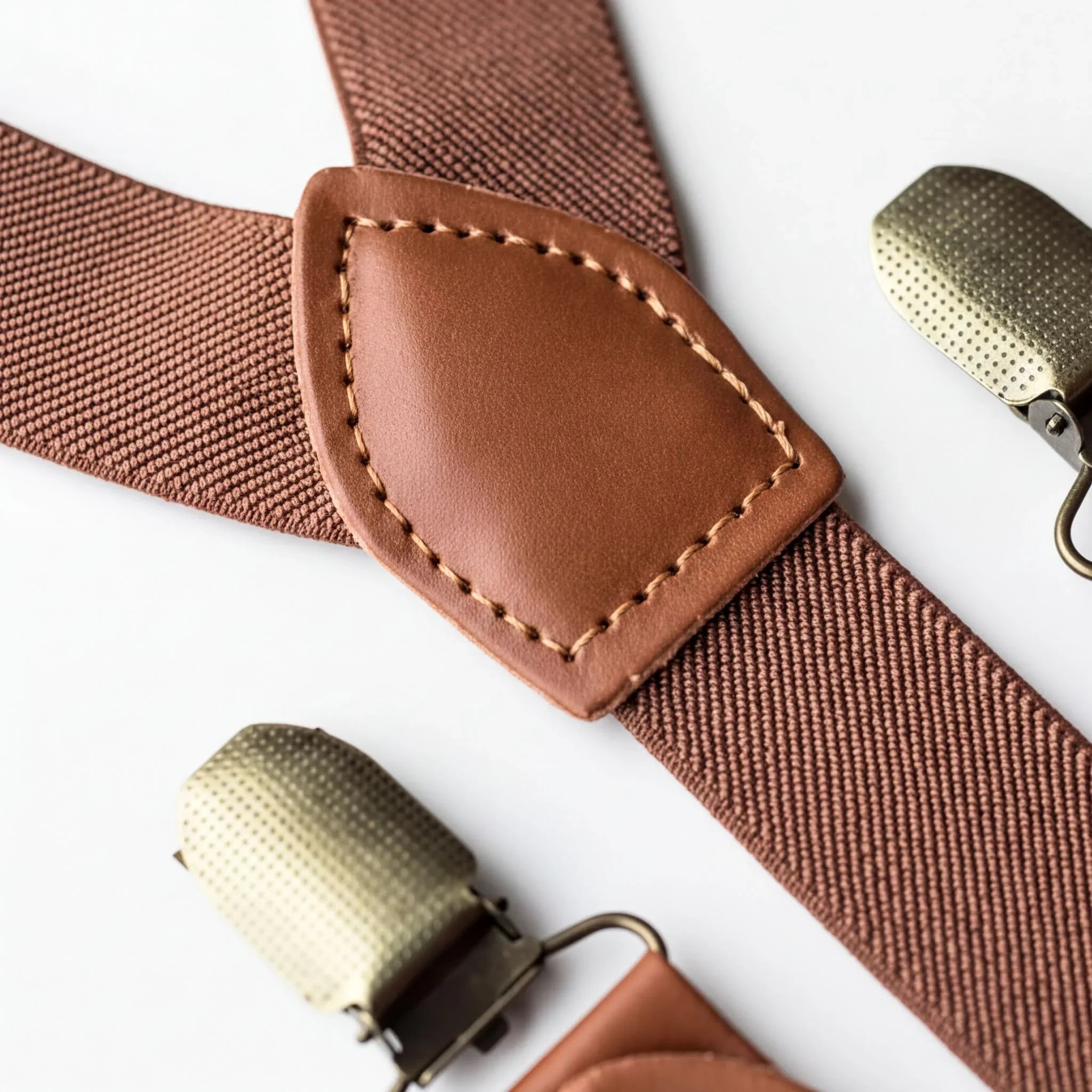 A close-up view of a brown leather suspender with a metal buckle, showing the buckle and the strap.