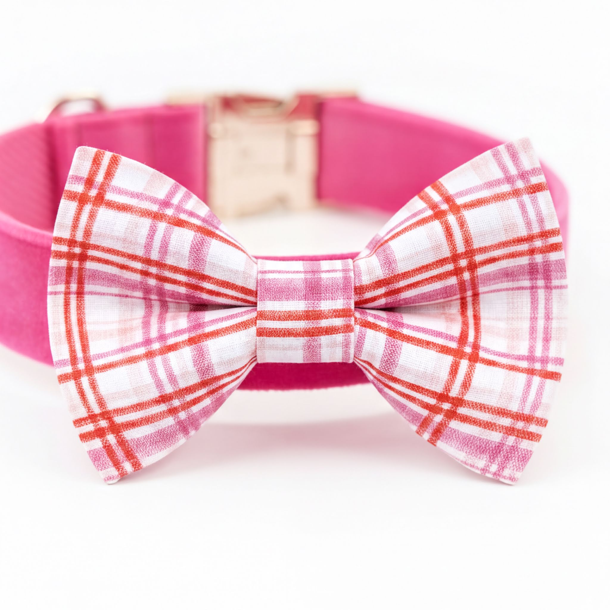 A pink collar with a bow tie featuring a plaid pattern.