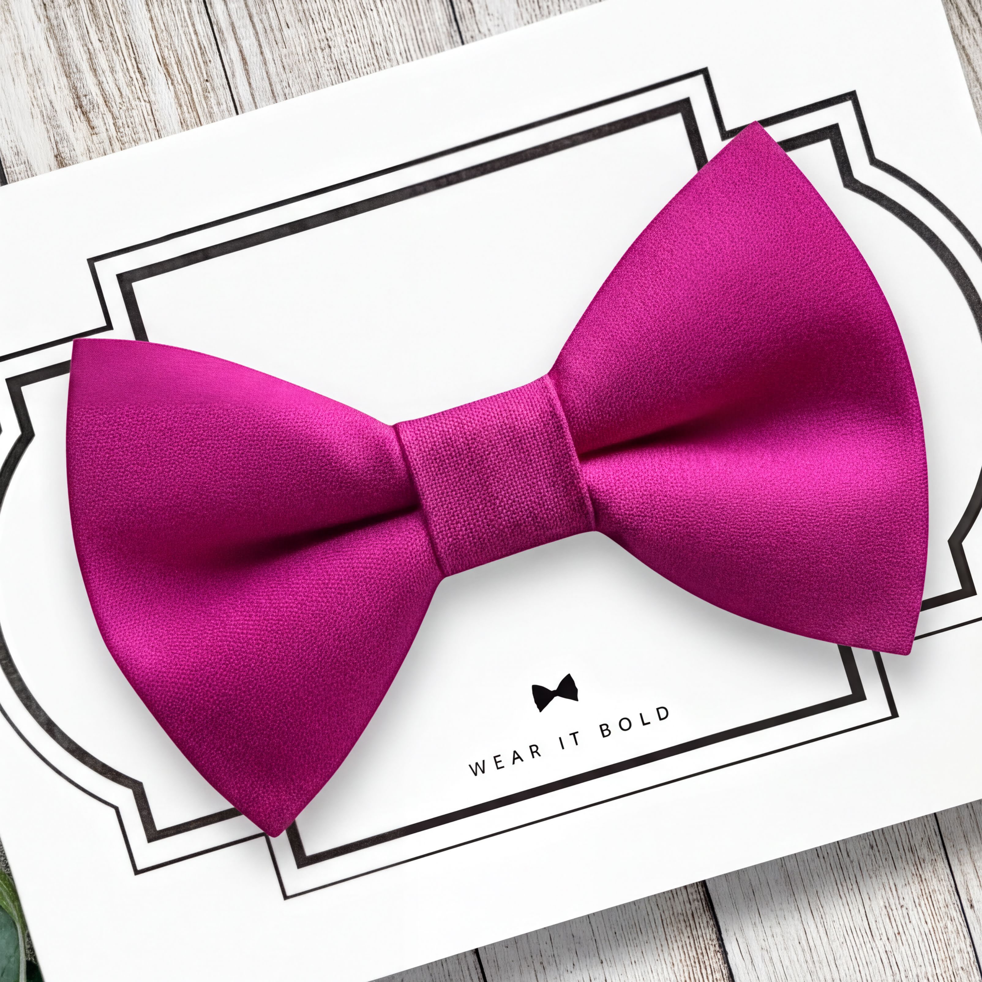 Hot pink dog bow tie on a white card with text on a wooden surface