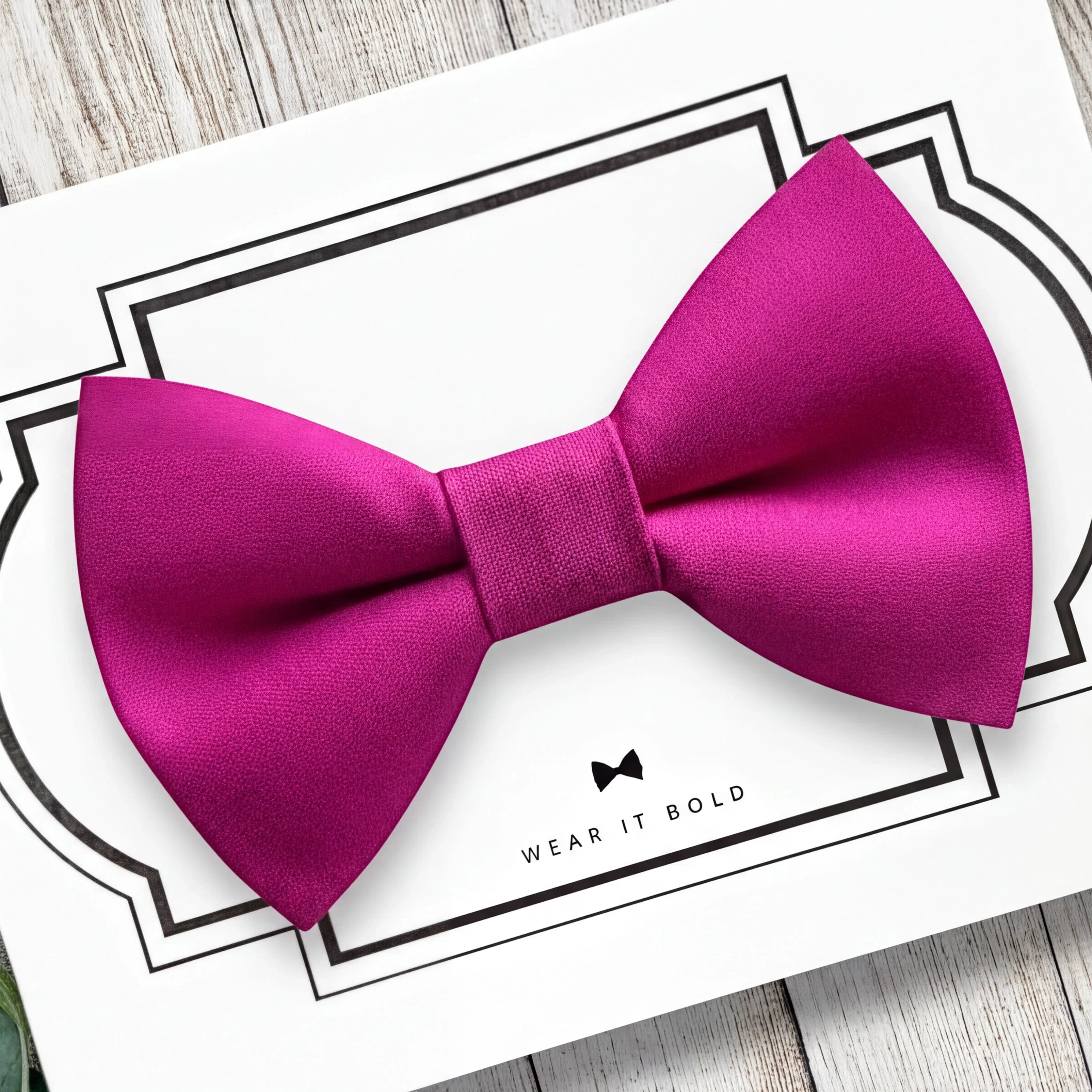 Hot pink dog bow tie on a white card with text on a wooden surface