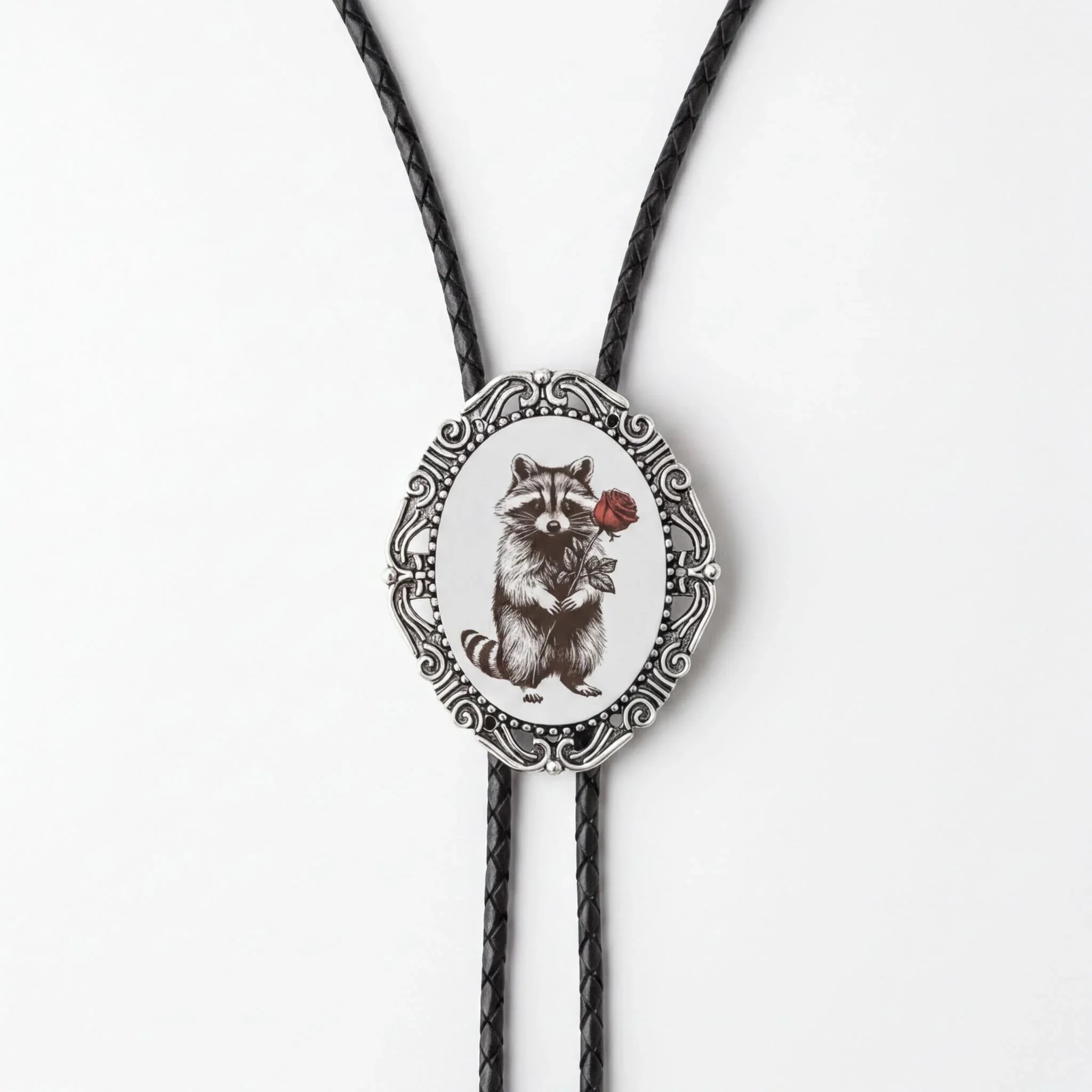 A silver oval-shaped pendant with a raccoon illustration on it, hanging from a black cord.