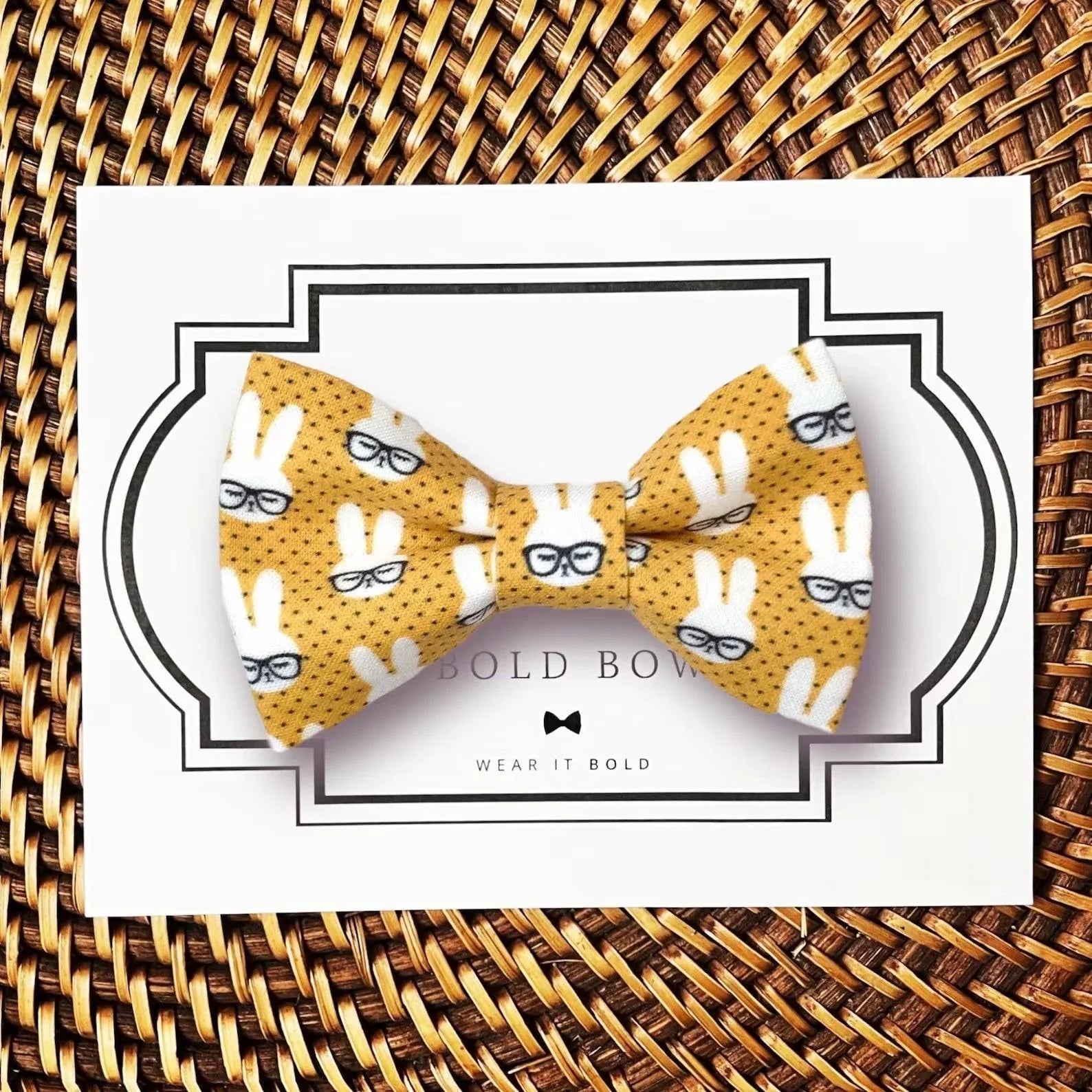 Yellow bow tie with white bunny silhouettes wearing glasses on a dotted background displayed on a card.