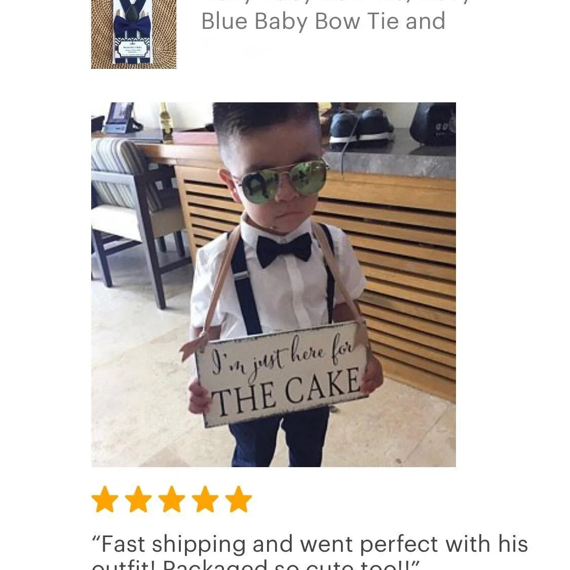 Young boy in white shirt navy satin bow tie and suspenders holding a sign that says I'm just here for the cake