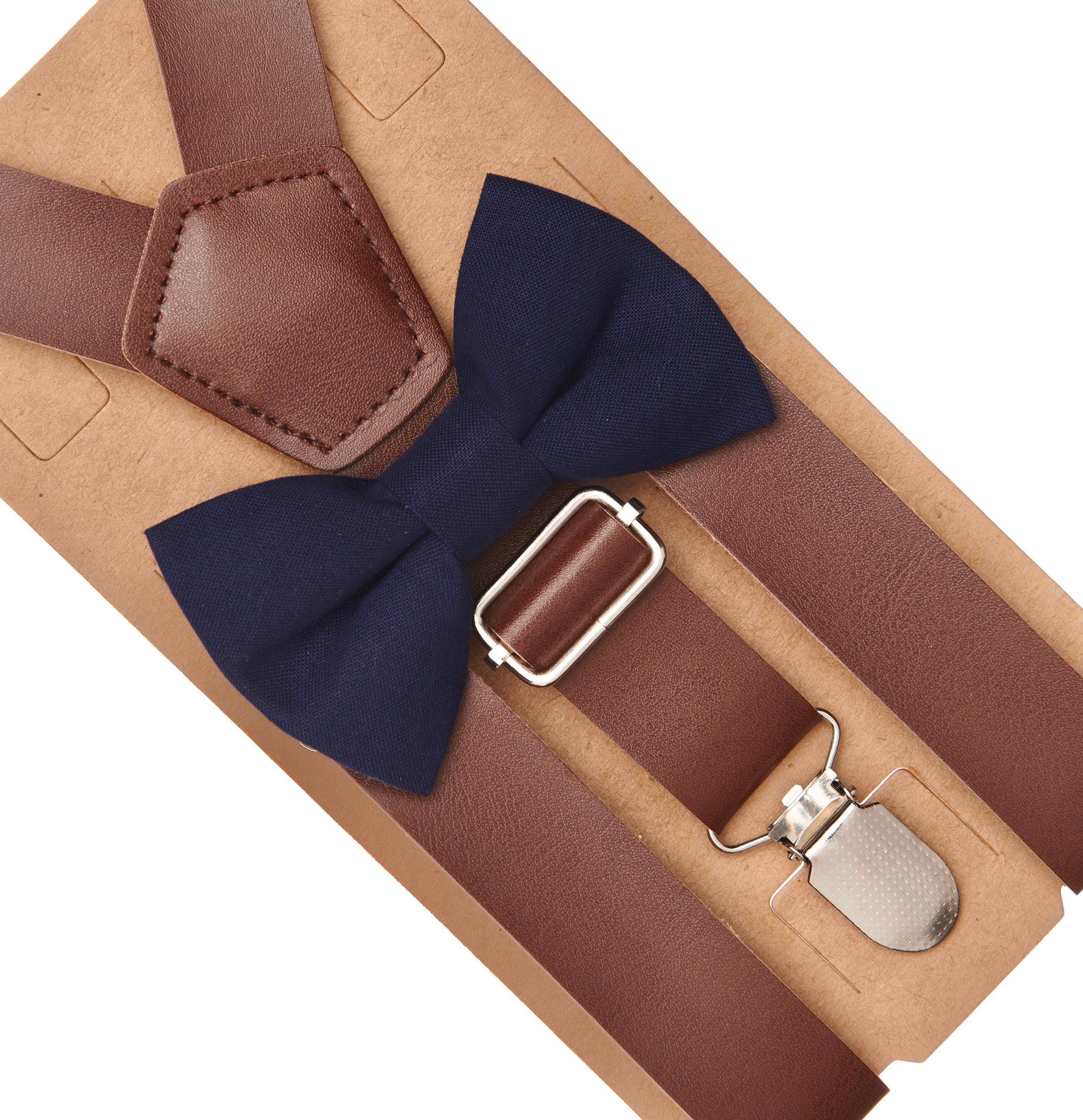 Brown suspenders with a navy bow tie and silver clip on a beige background