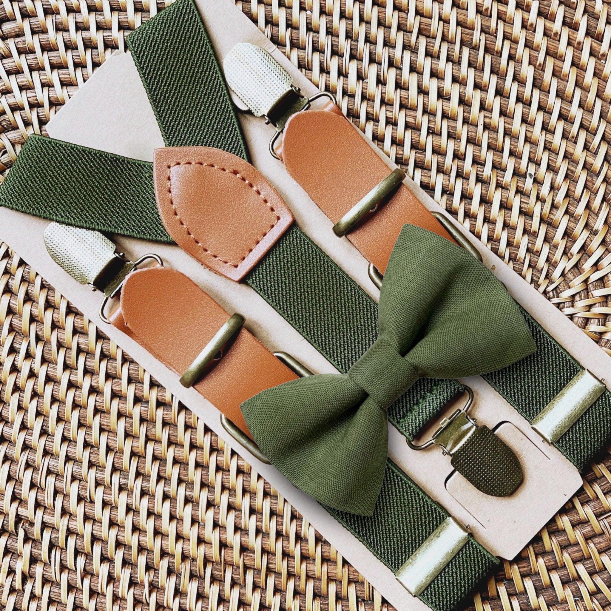 Olive bow tie and buckle suspenders arranged on a green textured strap with metal hardware.